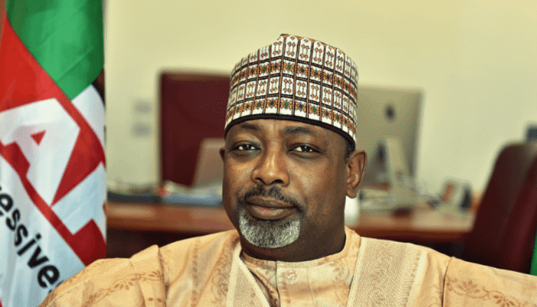Man in traditional attire seated before flag