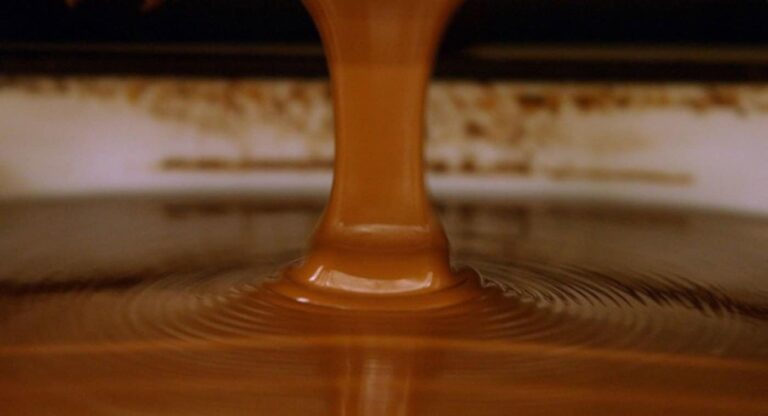 Caramel sauce pouring into liquid creating ripples