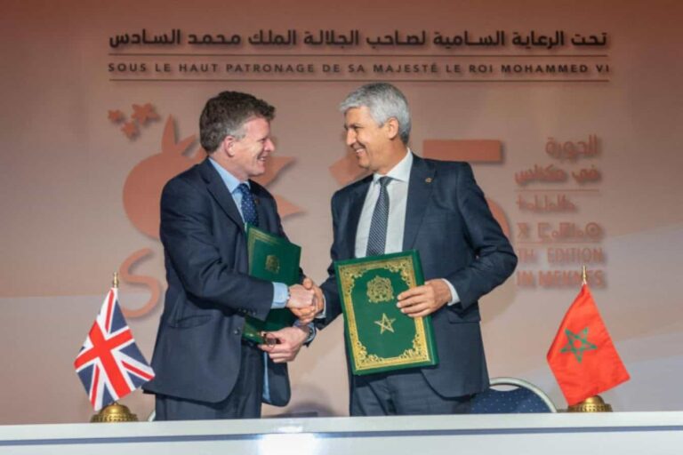 Two officials shaking hands with UK and Moroccan flags