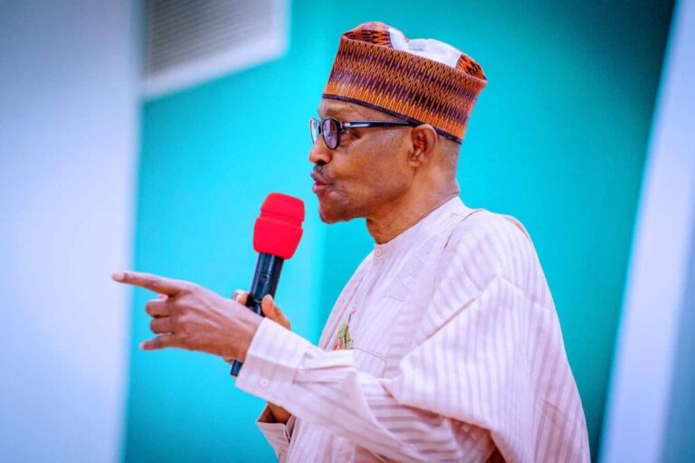 Man in traditional attire speaking into red microphone