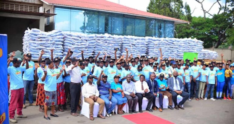 Large group posing before stacked aid sacks