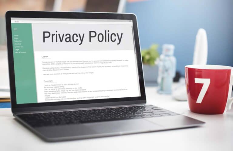 Laptop displaying privacy policy beside red mug