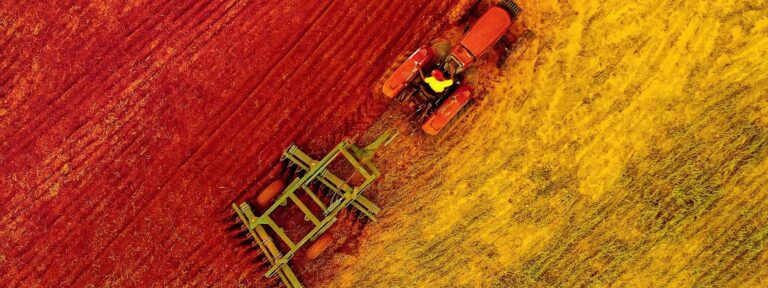Aerial view of tractor ploughing colourful farmland