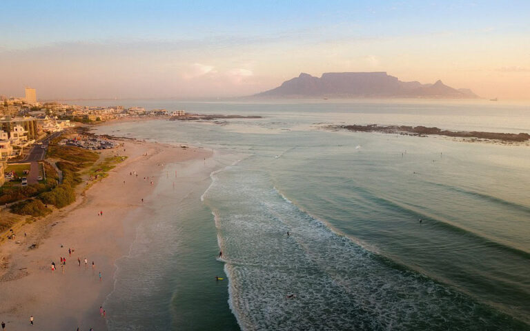 Beach and surfers with Table Mountain at sunset