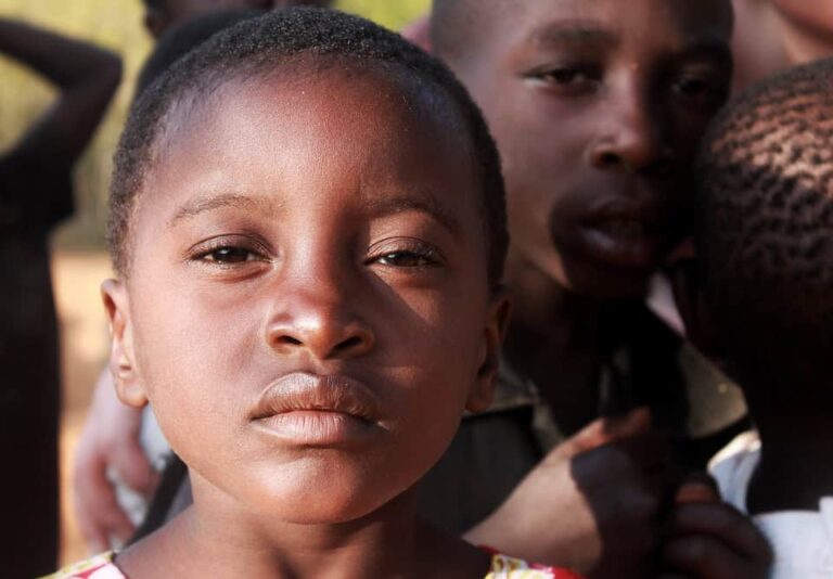 Close-up of young child outdoors with others behind