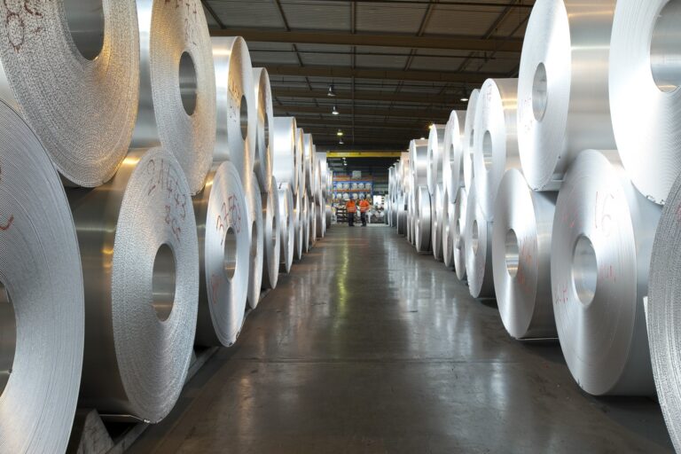 Large aluminium coils stored in warehouse aisle
