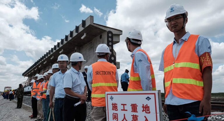 Construction workers in high-visibility vests at railway bridge site