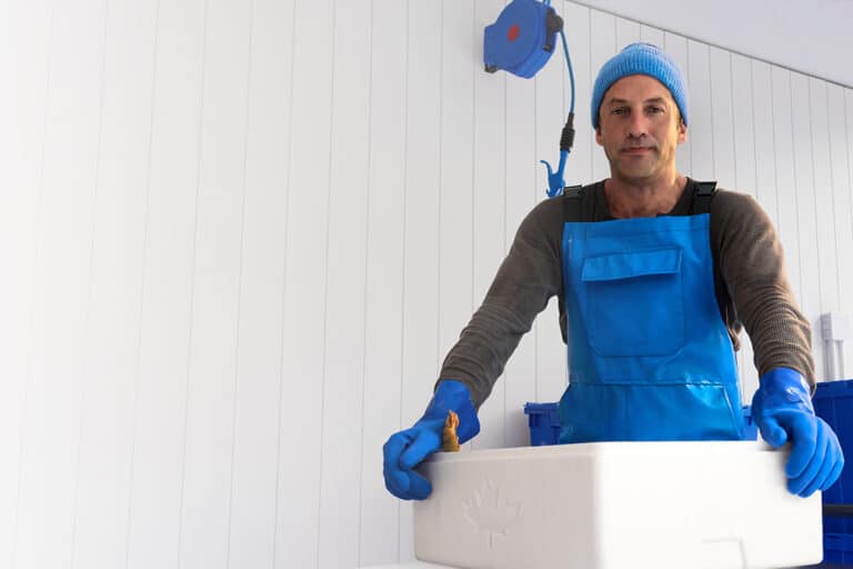 Fishmonger in blue apron holding insulated box
