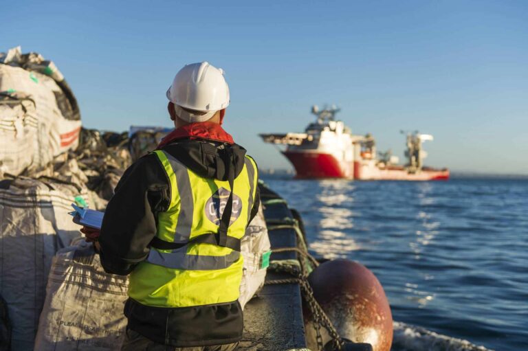 Port worker inspecting offshore vessel from dockside