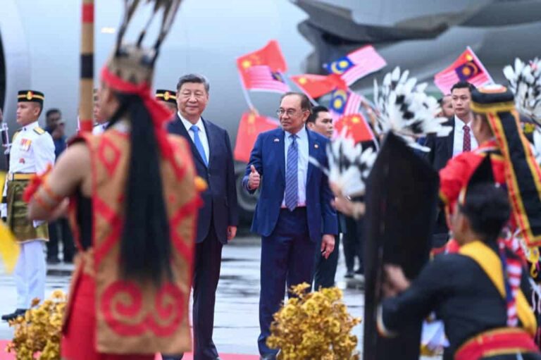 Officials welcomed by traditional dancers with Chinese and Malaysian flags